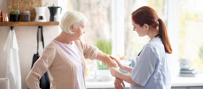 Caring red-haired nurse putting gel on arm for woman
