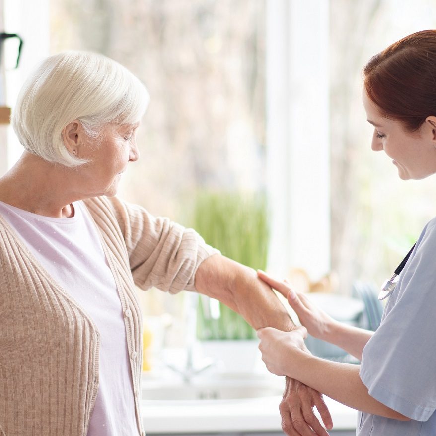 Caring red-haired nurse putting gel on arm for woman