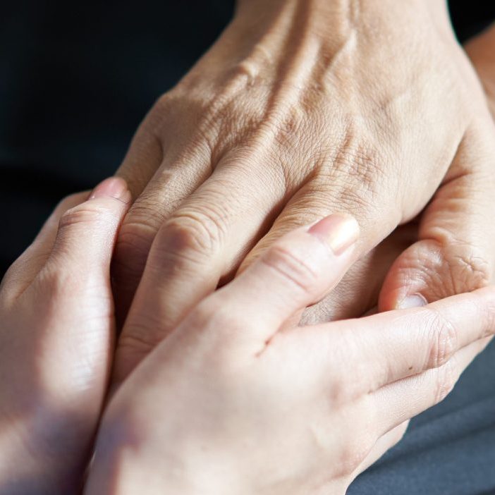 Hands of elderly people in wheelchairs and caregivers