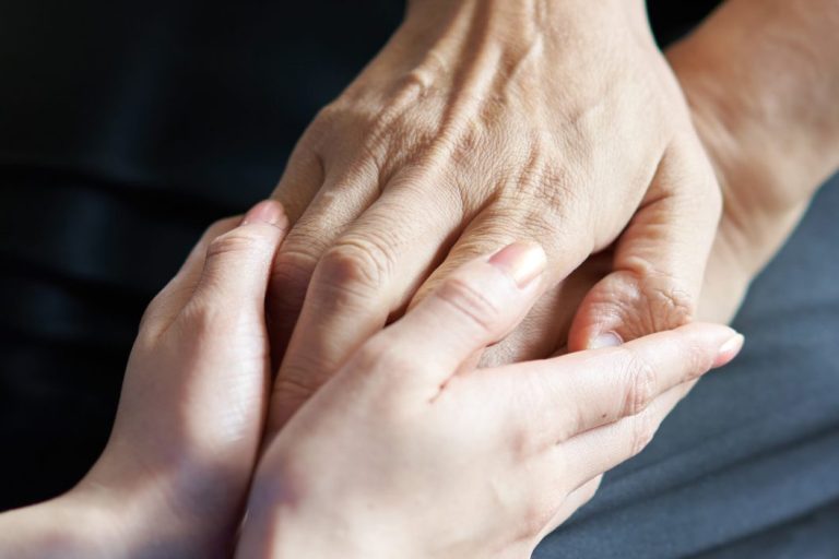 Hands of elderly people in wheelchairs and caregivers