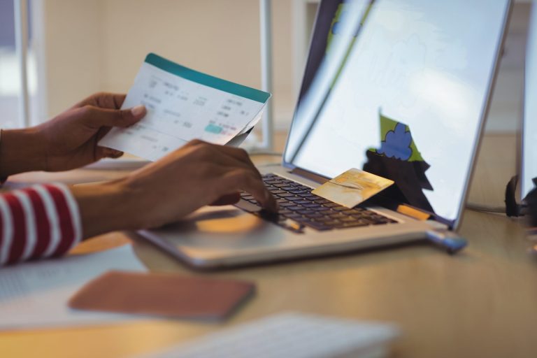Businesswoman holding documents while using laptop in office