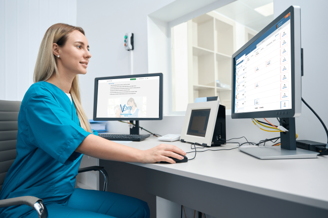 woman-in-blue-clothes-sits-at-a-table-and-works-at-2 Lady operating a computer with care software